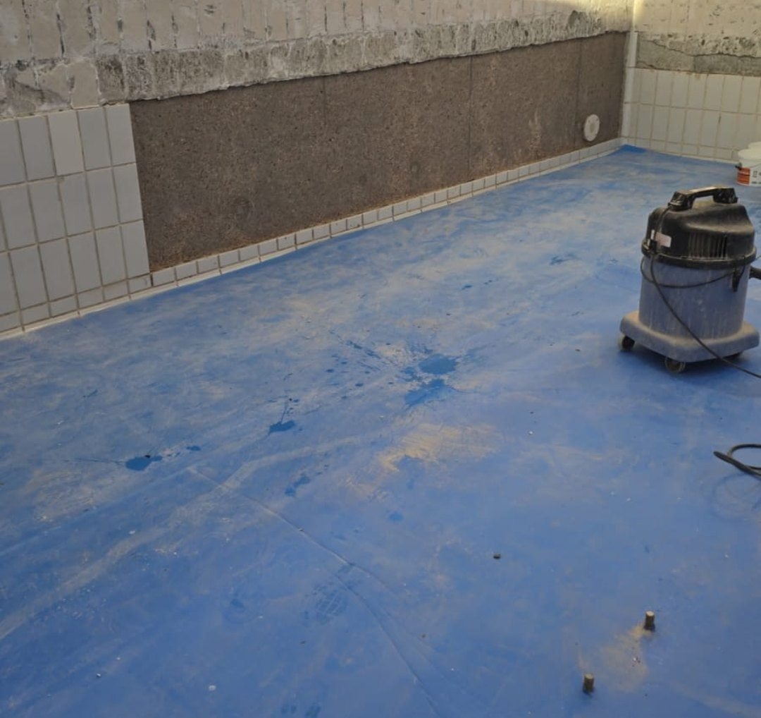 Pool wall re-rendered in a band ready for new tiles, with the floor protected